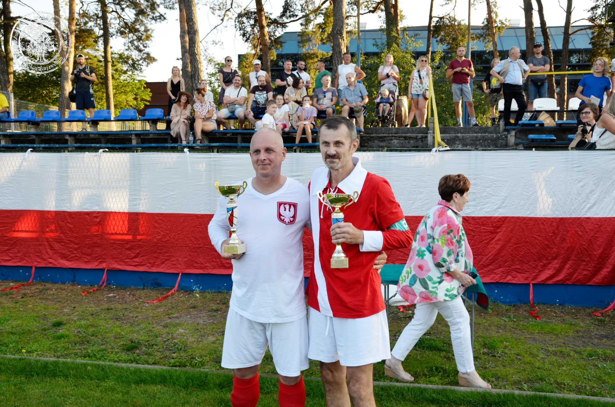 Kapitanowie obydwu zespołów z dumą prezentują pamiątkowe puchary za udział w meczu.