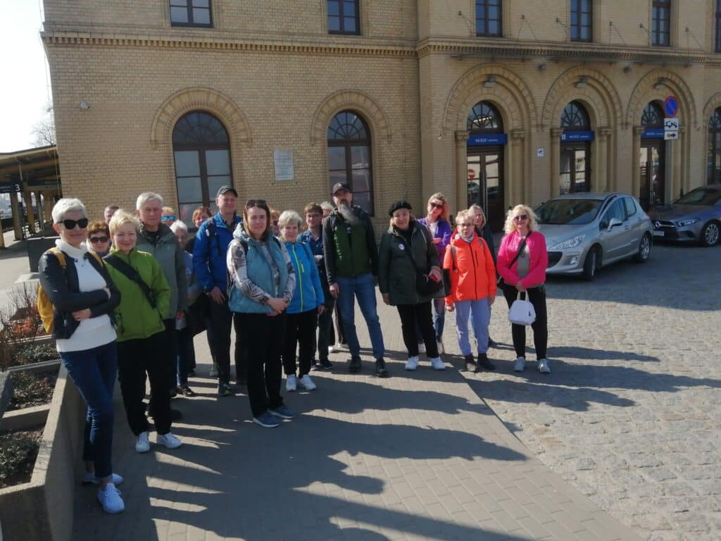 Zdjęcie przedstawia grupę osób stojących na tle dworca w Inowrocławiu.