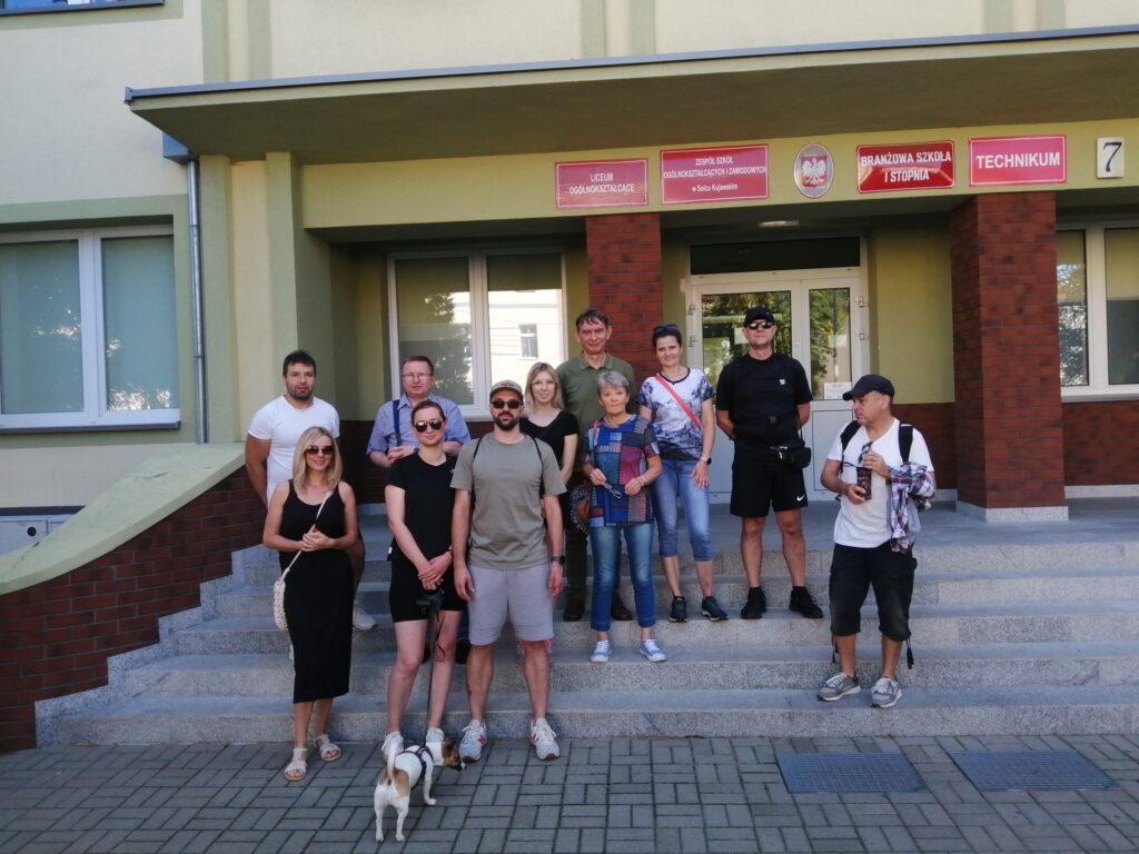 Grupa uczestników spaceru historycznego Śladami budynków użyteczności publicznej Solca Kujawskiego. W pogoni za przemysłem. Grupa pozuje na schodach budynku Zespołu Szkół Ogólnokształcących i Zawodowych w Solcu Kujawskim przy ulicy 29 Listopada.