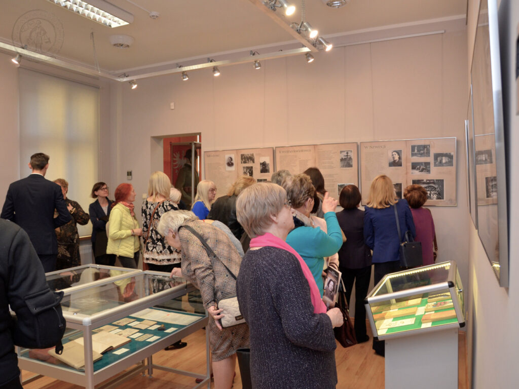 Zdjęcie przedstawia dużą salę wystaw czasowych podczas otwarcia wystawy. Goście oglądają antyramy i gabloty.